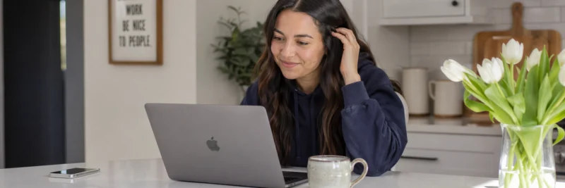 Woman at kitchen island comparing affiliate programs on a laptop