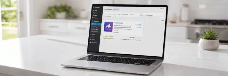 Laptop on a bright white kitchen island displaying the WordPress plugin directory with Rank Math SEO showing a 4.9 star rating and over 2 million installs as the best SEO plugin for WordPress